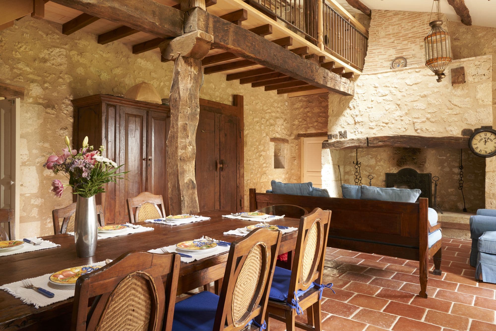The dining room with a long table laid for a meal beside a stone fireplace