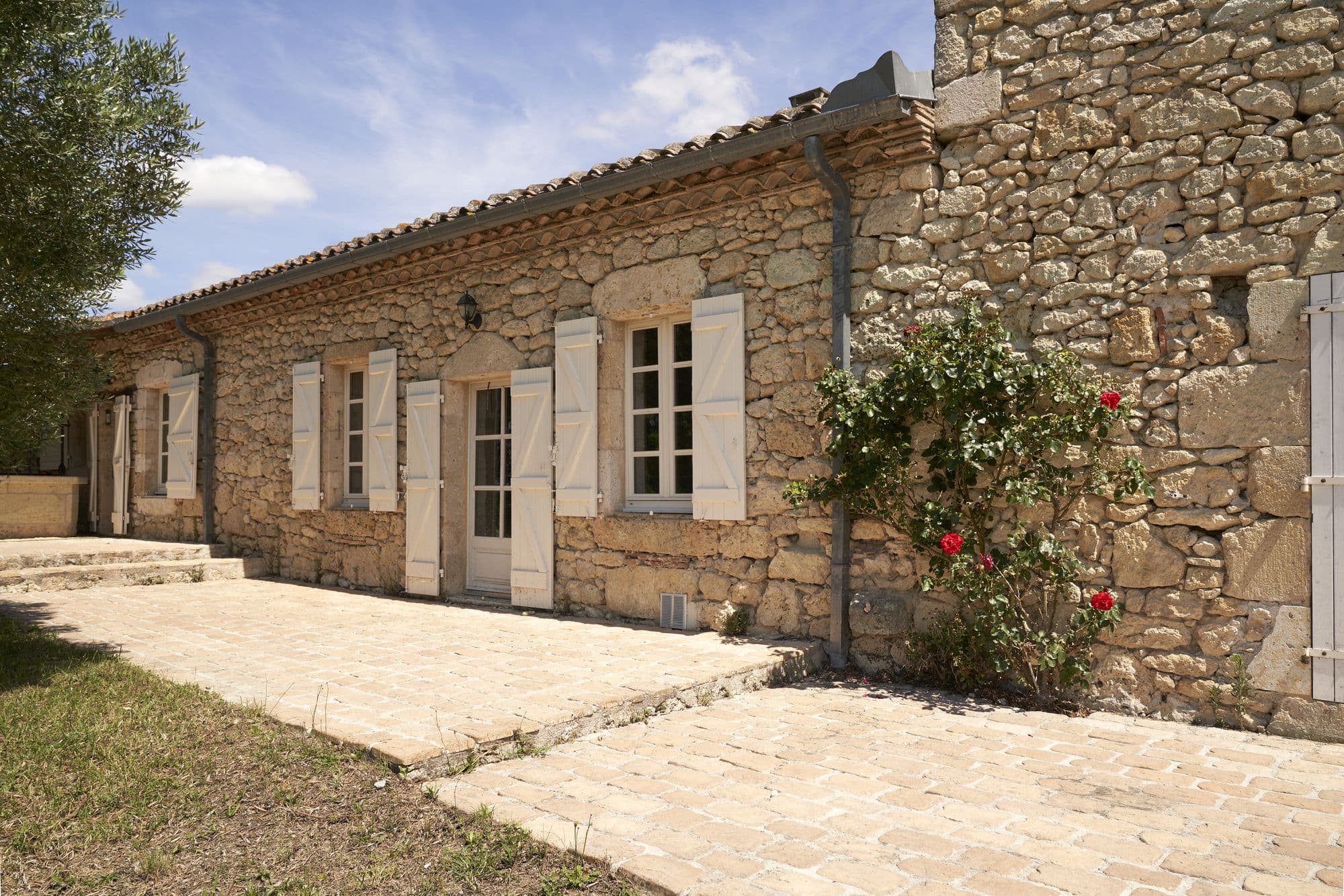 The stone facade of the house with roses climbing it