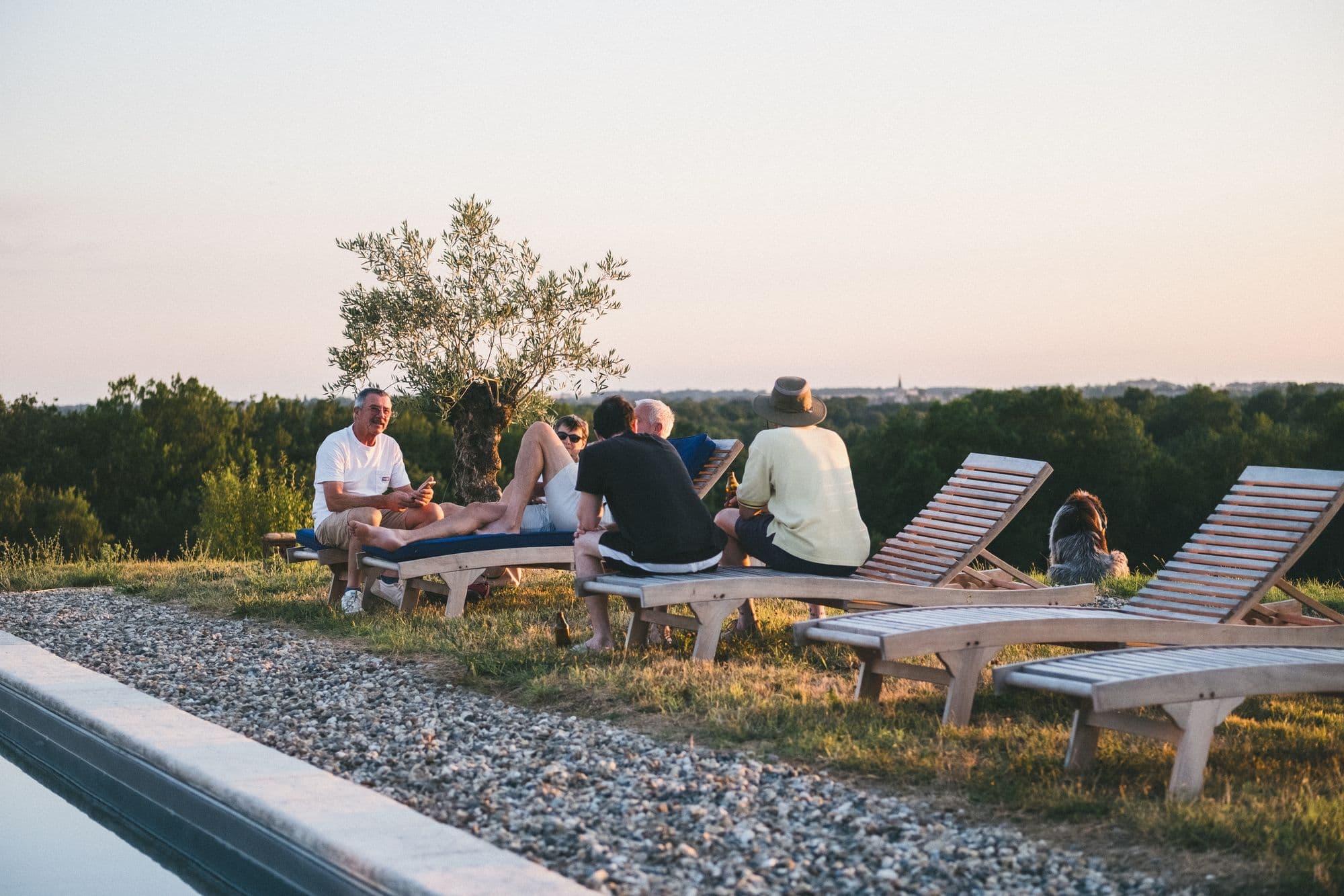Family sitting together by the pool in the evening