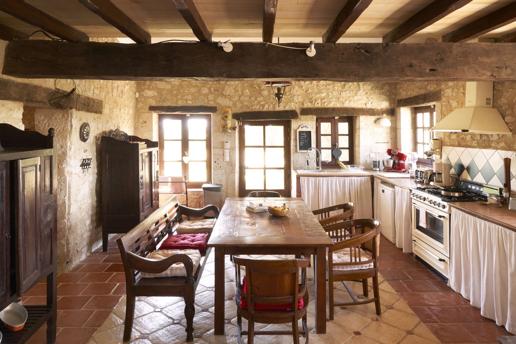 The kitchen with a range cooker, stone walls and terracotta floor