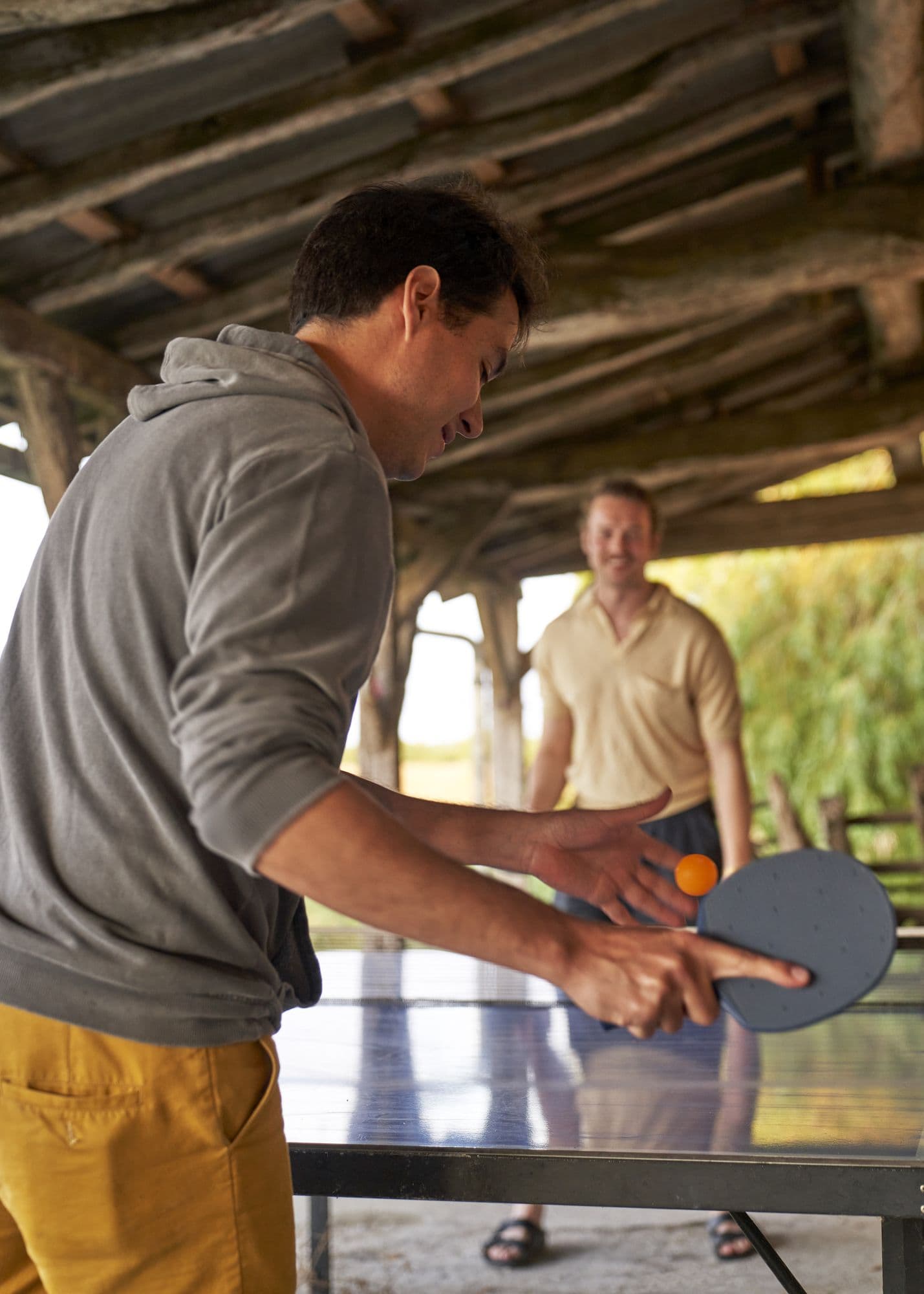 Two guests playing table tennis under the covered terrace