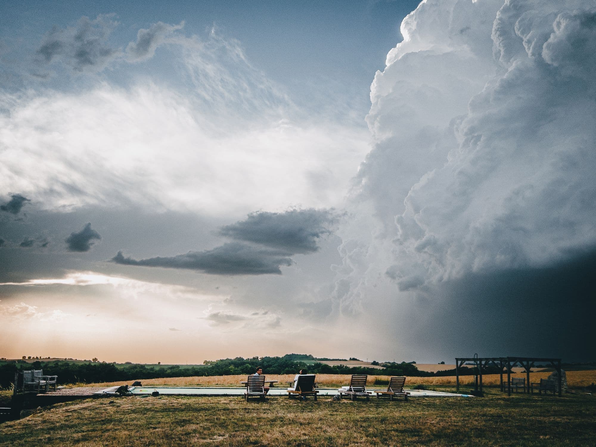 A storm cell building over the fields beyond the pool